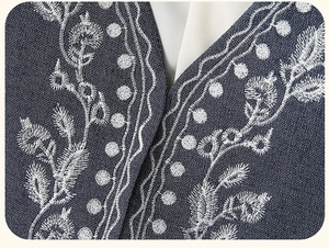 Detailed view of white floral embroidery on a vintage navy blue denim V-neck vest