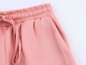 Detailed view of pink trousers with elastic drawstring waist and pleated texture fabric