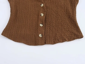 Close-up of brown textured fabric with single-breasted marble buttons on sleeveless vest