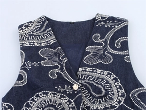 Gros plan détaillé du gilet en denim bleu foncé avec broderie paisley blanche et bouton doré