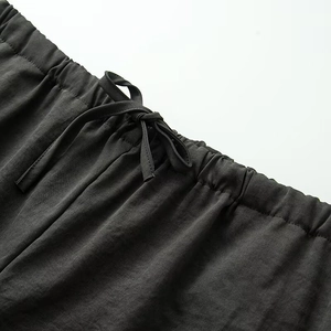 Dettaglio della vita elastica su pantaloni grigio scuro con coulisse e trama fine del tessuto