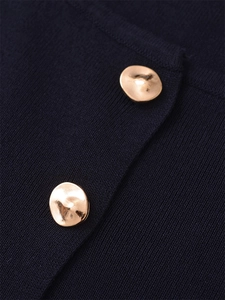 Detail of dark knit fabric featuring irregular golden buttons and fine texture