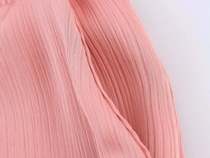Macro shot of vertical pleated fabric texture and side pocket detail on pink women suit