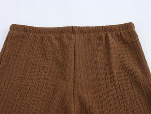 Detail of high-waist elastic band and vertical pleated texture on brown trousers