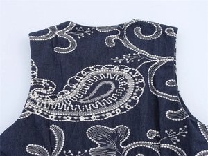 Gros plan de la broderie paisley blanche sur le haut sans manches en denim bleu foncé