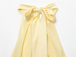 Detail of light yellow satin dress featuring a large decorative bow neckline