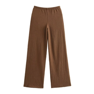 Detail of deep brown wide-leg trousers showing vertical pleated texture and elastic waist