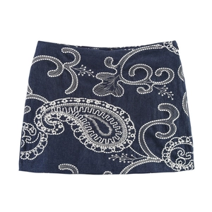 Détail d'une mini-jupe en jean bleu foncé avec une broderie cachemire blanche