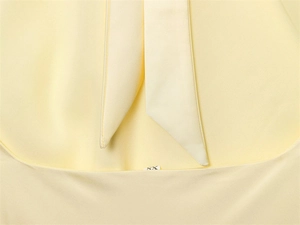Detailed close-up of light yellow dress neckline with tie design and size XS tag