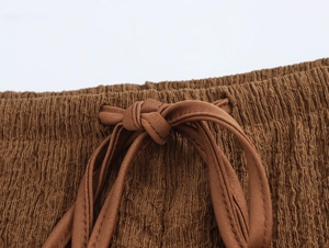 Detail of brown crinkled fabric with elastic waistband and decorative drawstring tie