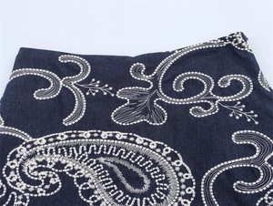 Détail d'un short en jean bleu marine avec broderie paisley blanche et fermeture éclair invisible
