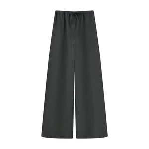 Dettaglio di pantaloni neri a gamba larga con vita elastica e coulisse su sfondo bianco