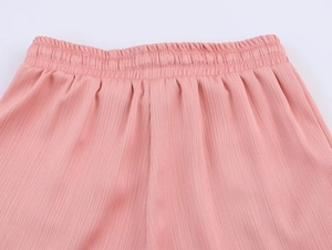 Detail of pink pleated trousers showing elastic waistband and vertical texture
