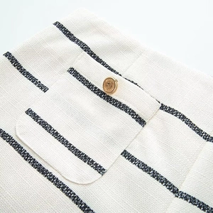 Detail of white striped tweed fabric with vintage gold button and textured pocket