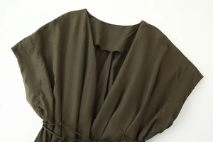 Detail of deep olive green V-neck dress with waist drawstring and pleated fabric