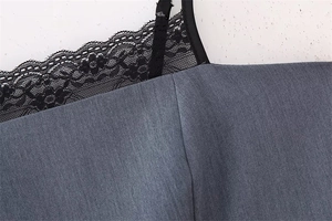 Close-up of fine black floral lace trim and delicate straps on dark gray summer dress