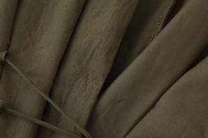 Detail of army green fabric texture with fine stitching and drawstring on the V-neck dress