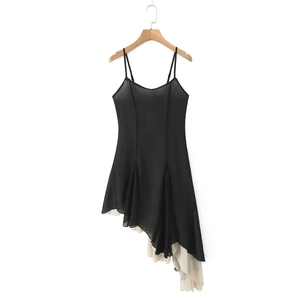 Detail of black V-neck slip dress showing asymmetric layered hem with cream chiffon fabric