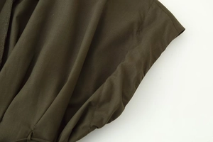 Macro detail of military green dress showing precise stitching and pleated fabric texture
