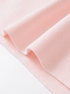 Macro shot of soft pink ribbed knit fabric showing detailed texture and soft material