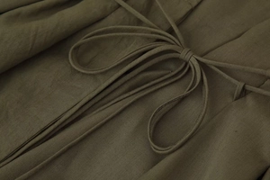 Detail of olive green V-neck dress showing textured cotton linen fabric and tie-up drawstring