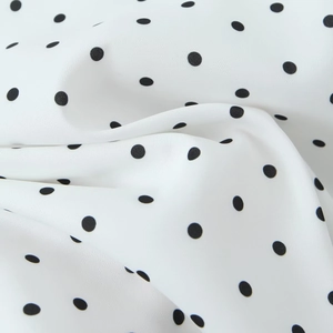 Gros plan d'un tissu blanc léger avec des pois noirs classiques et une texture douce