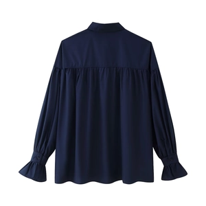 Detail of navy blue shirt back featuring pleated yoke and ruffled flared cuffs