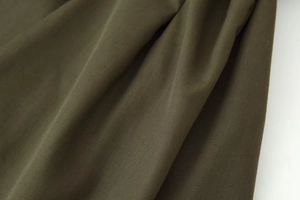 Detailed macro shot of olive green pleated fabric texture with premium cotton weave