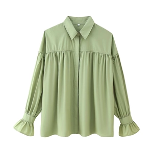 Detail of sage green shirt showing pleated front texture and flared bell cuff sleeves