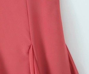 Detail of coral pink sleeveless dress showing side seam stitching and soft fabric draping