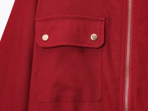 Detail of red textured jacket featuring square pocket with gold buttons and metal zipper