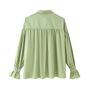 Detail view of the pleated back design and ruffled cuffs on this light green lapel blouse