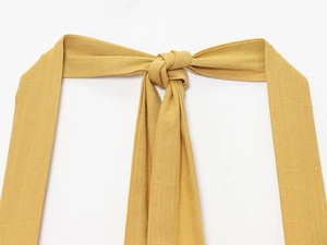 Gros plan des bretelles licou jaune gingembre avec texture de tissu et détail de nœud