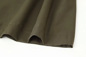 Detail of army green dress hem showing professional double-needle stitching and fabric texture