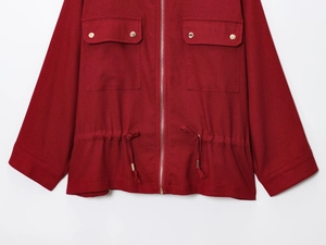 Detail of wine red jacket with golden zipper, flap pockets and adjustable drawstring waist