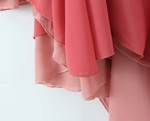 Detail view of coral pink chiffon dress showing multi-layered pleated hem and stitching