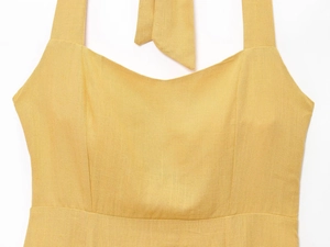 Détail de la robe en lin jaune gingembre avec larges bretelles et nœud décoratif au cou