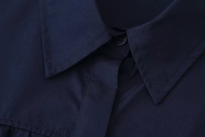 Macro detail of navy blue lapel collar with fine stitching on smooth woven fabric