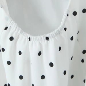 Détail de l'encolure élastique et de l'imprimé à pois noirs sur tissu mousseline blanc