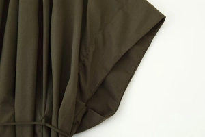 Detailed close-up showing fine stitching and pleated texture of olive green V-neck dress