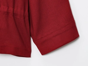 Macro view of drawstring waist and precise stitching on rust red woven jacket sleeve