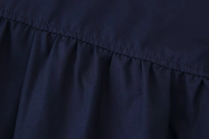 Macro shot of navy blue shirt featuring smocked fabric detail and double stitching finish