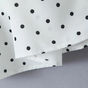 Gros plan détaillé du tissu blanc à pois noirs avec couture fine sur l'ourlet de robe