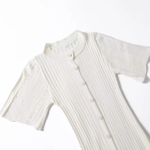 Detail of white knit dress showing vertical ribbed texture and delicate hollow-out sleeves