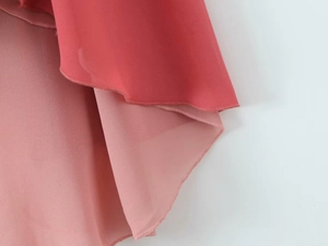 Detail of coral chiffon fabric showing premium rolled hem stitching and layered texture