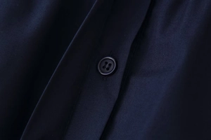 Macro detail of navy shirt fabric showing the button and fine stitching quality