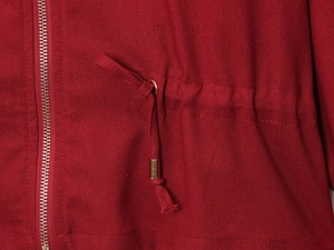 Close-up of red jacket featuring metal zipper and adjustable drawstring with gold tips