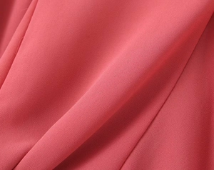 Detailed macro view of pink crinkled crepe fabric texture with fine stitching details