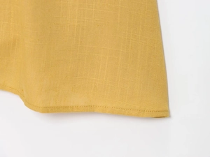 Gros plan sur l'ourlet en lin jaune gingembre montrant la texture et les coutures nettes