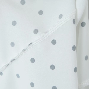 Détail du tissu mousseline à pois blancs montrant des coutures fines et lisses